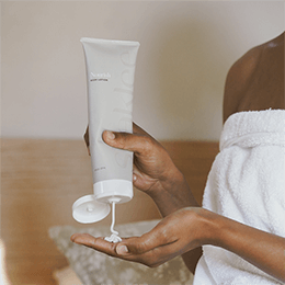 Woman squeezing Nourish Body Lotion out of tube